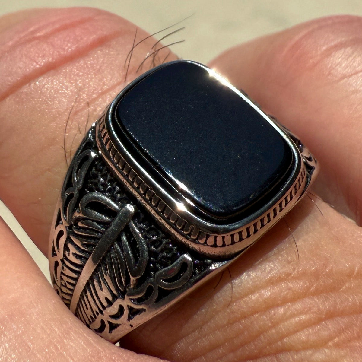 Silver ring with a black stone on a finger