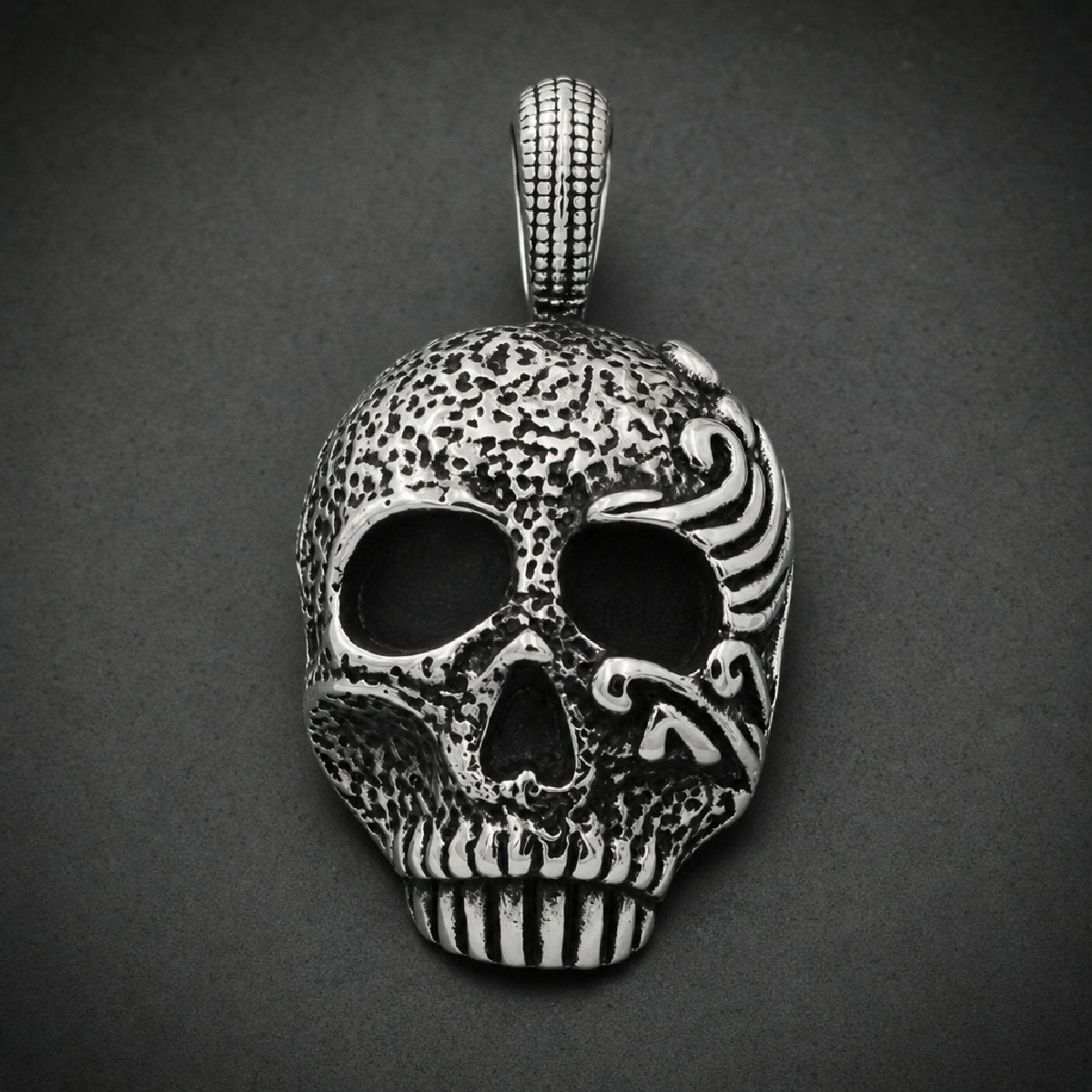Damnatio Cranium Pendant in 316L surgical stainless steel featuring pitted skull texture and polished filigree eye scrollwork