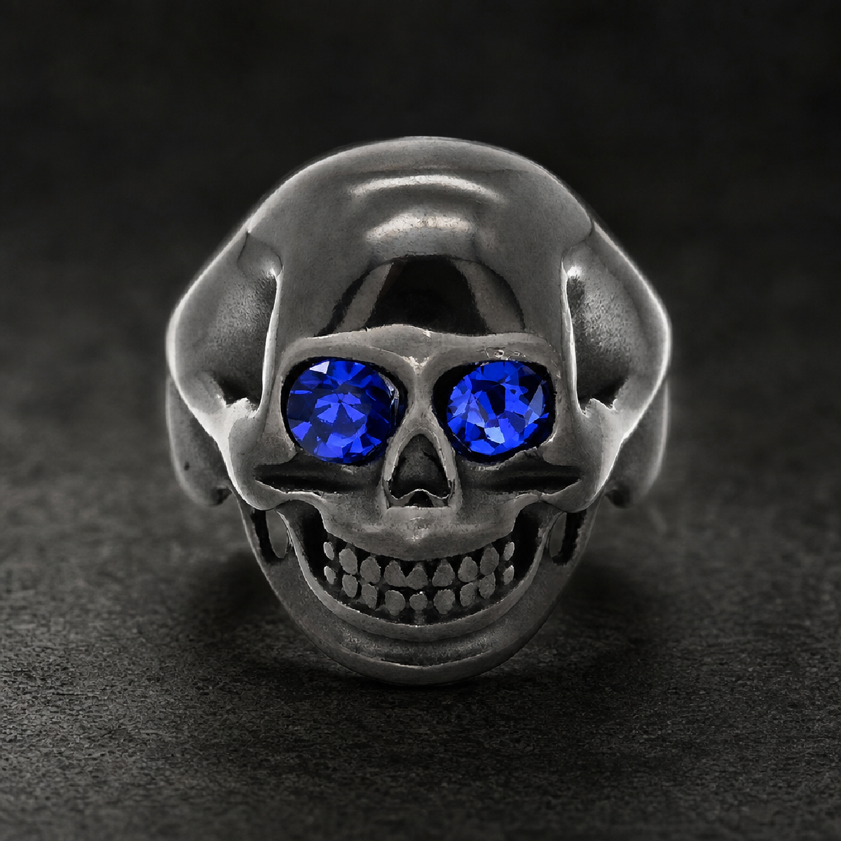 Bold HardKnocker black oxidized 316L surgical-grade stainless steel skull ring with two vivid blue gemstone eyes.