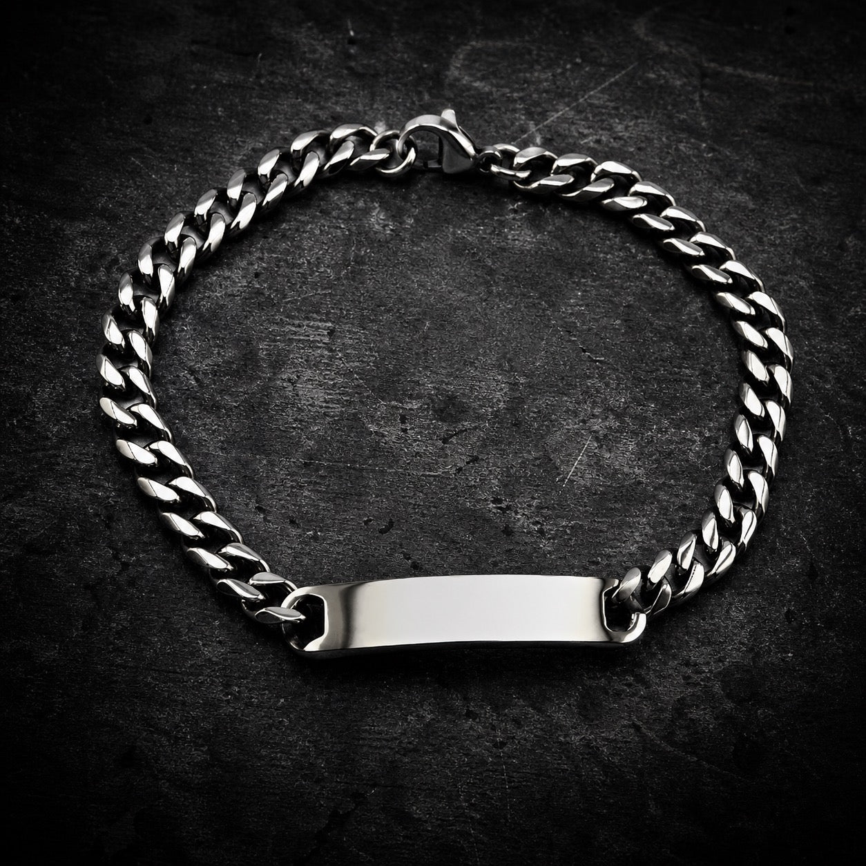 Highly polished 316L stainless steel curb chain bracelet with a smooth, blank rectangular ID plate, featuring a lobster clasp closure, on a white background.