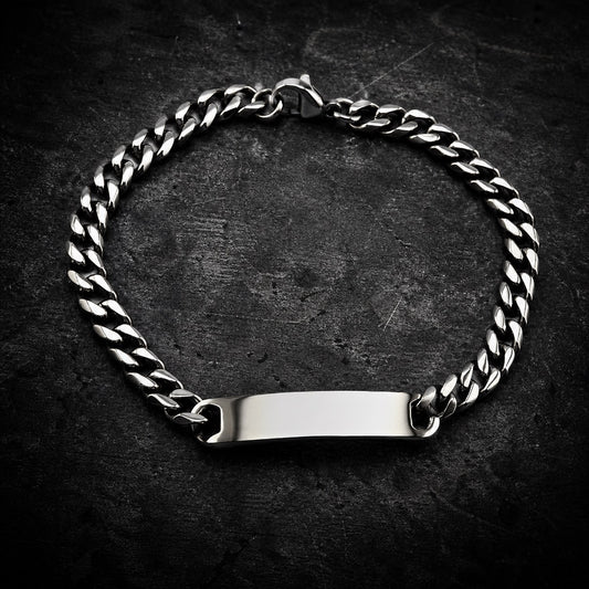 Highly polished 316L stainless steel curb chain bracelet with a smooth, blank rectangular ID plate, featuring a lobster clasp closure, on a white background.
