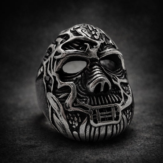 Silver skull ring with intricate designs on a dark background