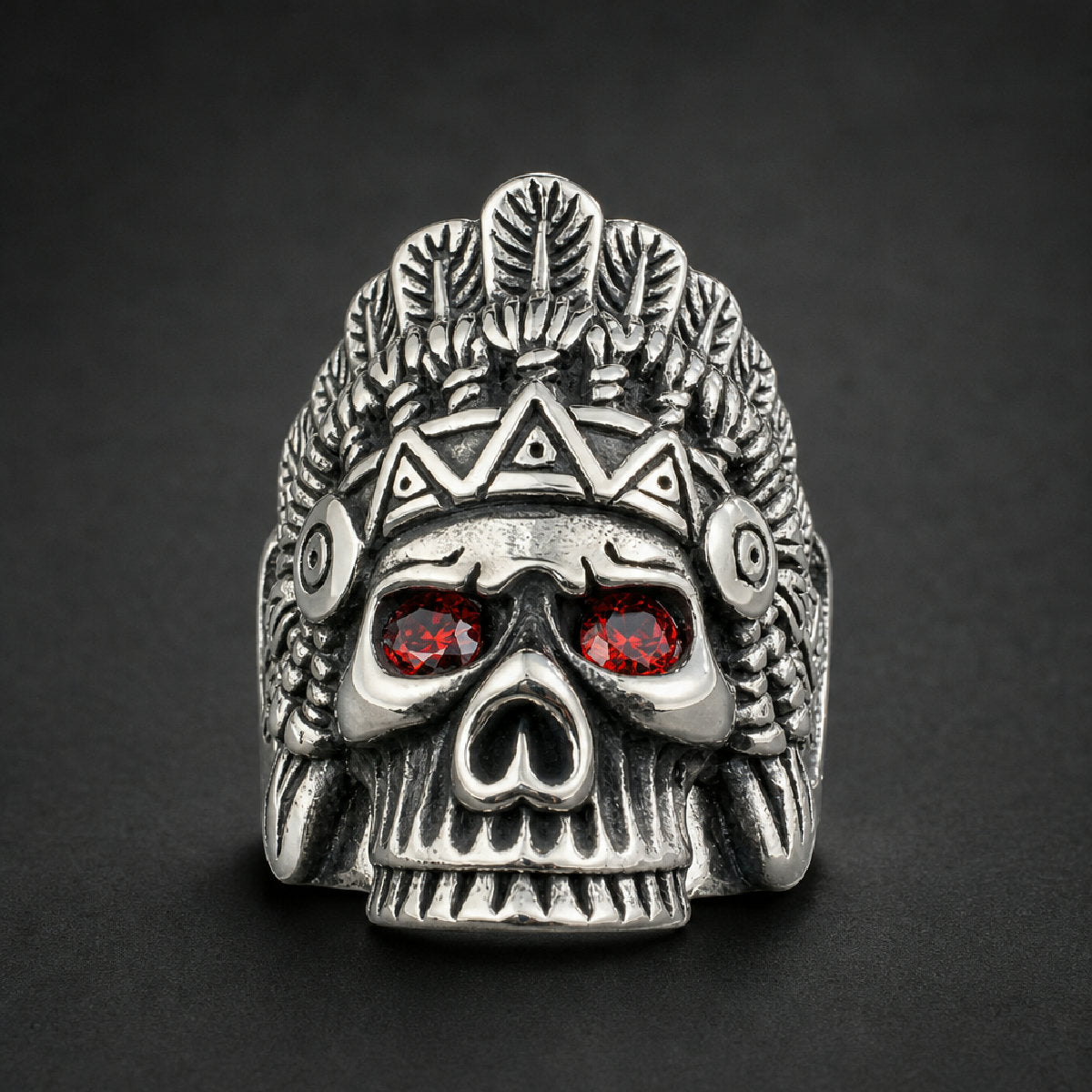 Bold Bone Chief Ring in 316L surgical stainless steel, featuring a skull adorned with a detailed feathered headdress and two striking red gem eyes.