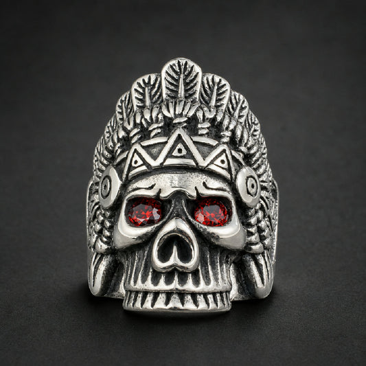 Bold Bone Chief Ring in 316L surgical stainless steel, featuring a skull adorned with a detailed feathered headdress and two striking red gem eyes.