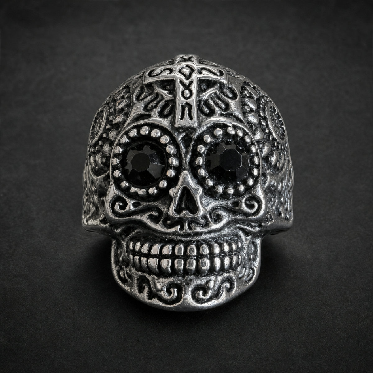 Heavy 316L stainless steel ring with an ornate sugar skull design, featuring dark black faceted gemstone eyes and intricate scrollwork, in an antiqued silver finish.