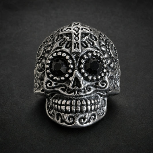 Heavy 316L stainless steel ring with an ornate sugar skull design, featuring dark black faceted gemstone eyes and intricate scrollwork, in an antiqued silver finish.