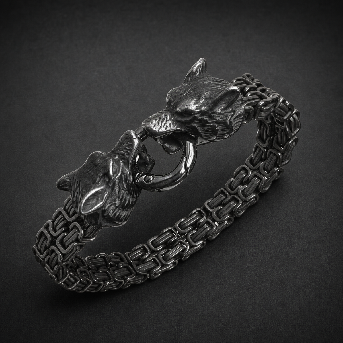Heavy 316L stainless steel bracelet with two detailed wolf heads clasping a ring, featuring an oxidized finish and robust linked chain.