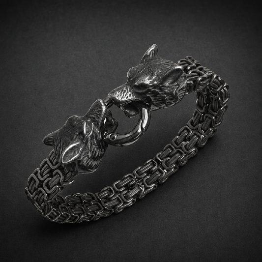 Heavy 316L stainless steel bracelet with two detailed wolf heads clasping a ring, featuring an oxidized finish and robust linked chain.