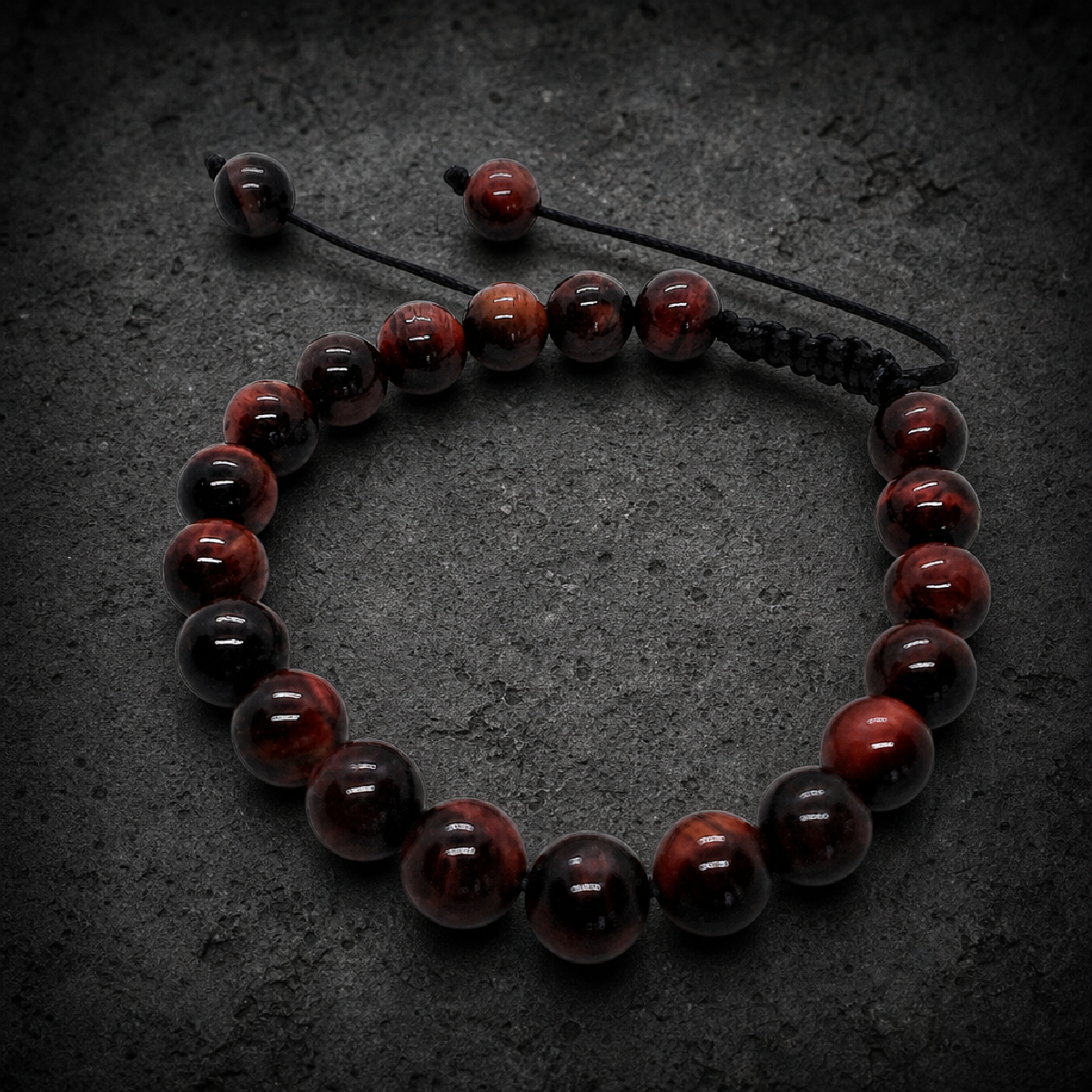 A close-up of a natural Red Tiger Eye adjustable bead bracelet with polished round beads, ranging from deep red to reddish-brown with visible chatoyance. A US dime is placed in the center for scale. The bracelet is on a white surface, with a black macrame-style cord.