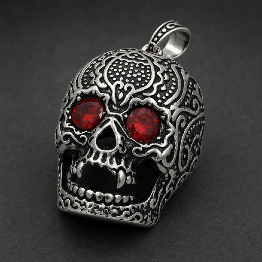 Detailed 316L stainless steel skull pendant with carved filigree, sharp fangs, and red gem eyes