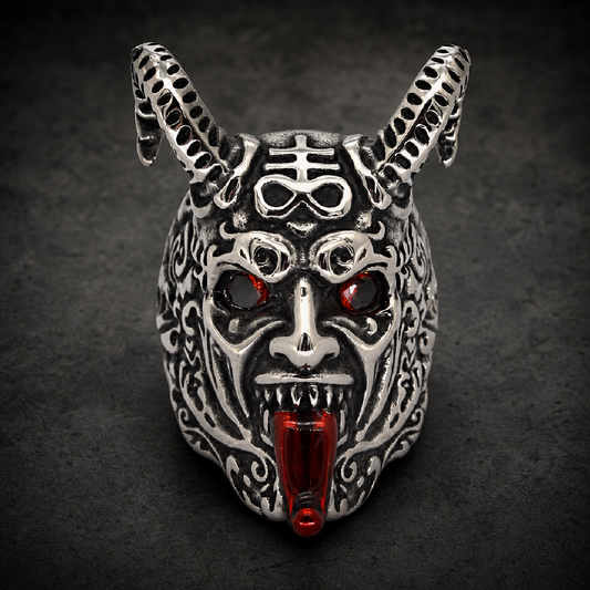 A heavy gauge 316L surgical stainless steel ring featuring a highly detailed, silver polished demon head with prominent horns, glowing red gemstone eyes, and a striking red enameled tongue. The demon head is intricately sculpted with a fierce design, showcasing an inverted pentagram symbol on its forehead.
