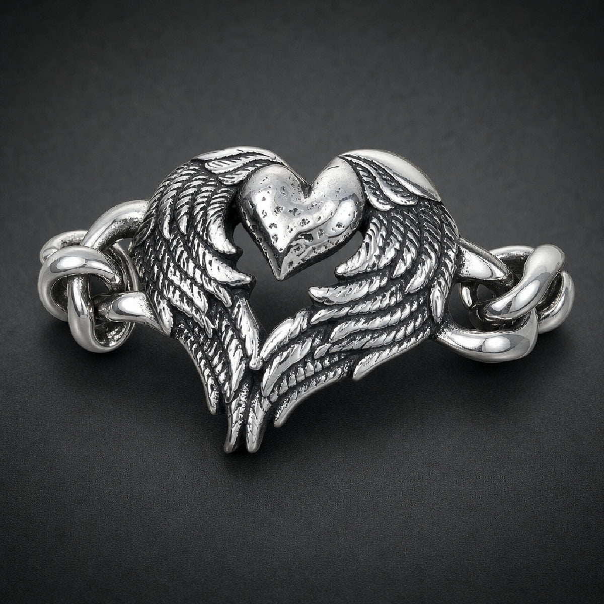 Unisex 316L stainless steel bracelet featuring a textured heart framed by detailed feathered wings and heavy curb links