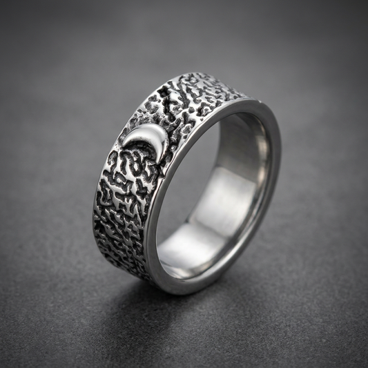 Lunar Crater Ring made of 316L stainless steel with deeply textured, dark cratered surface and a crescent moon symbol.