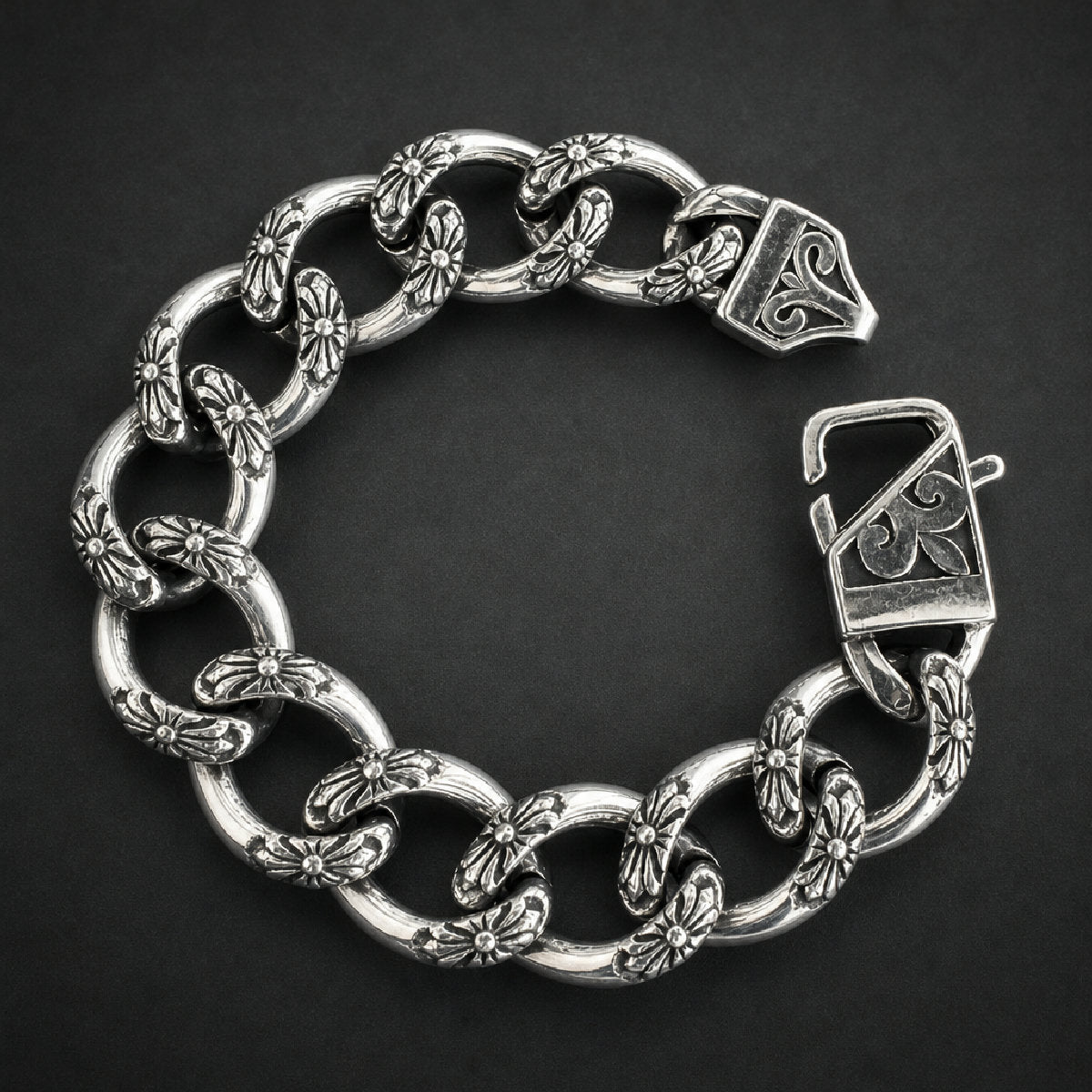 Heavy 316L stainless steel bracelet with intricate floral cross-like etched links and a decorated clasp, bright silver finish.