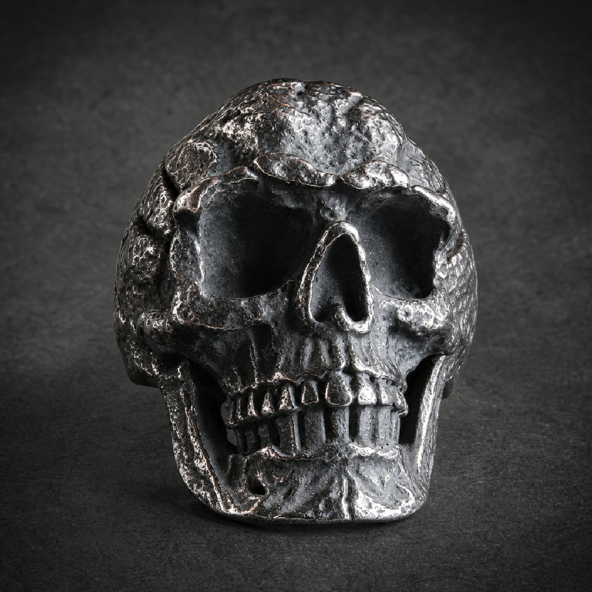 Heavy-duty 316L surgical stainless steel skull ring with deep-set eyes, grimace, and textured, weathered finish.