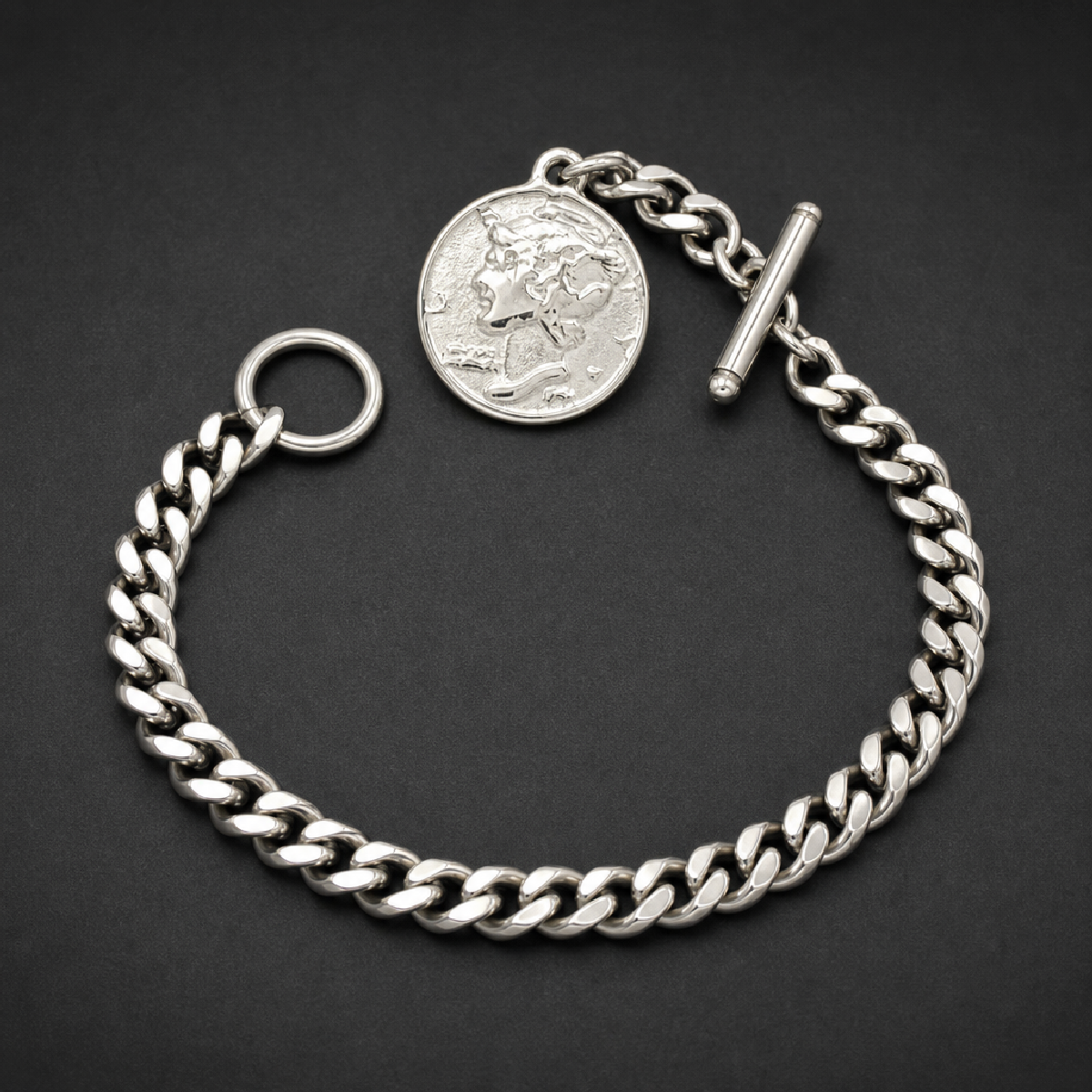 Heavy 316L stainless steel cuban link chain bracelet with a large round silver medallion featuring a profile of a face, secured by a toggle clasp.