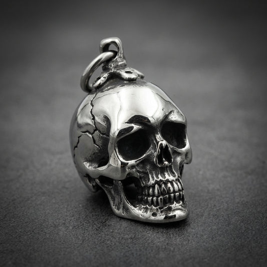 Heavy-duty 316L stainless steel skull pendant with oxidized details and a high-polish finish, held in a hand.