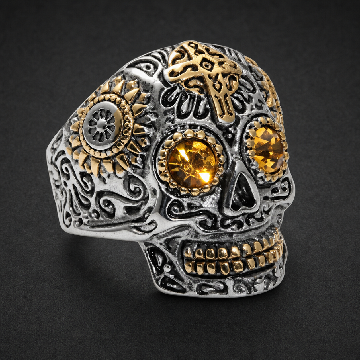Ornate sugar skull ring, 316L stainless steel, with golden accents and bright amber colored gemstone eyes on a black background.