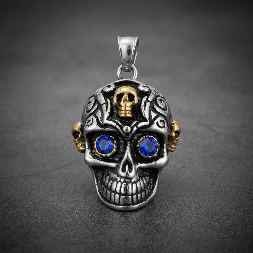 Prime Skull Pendant in 316L stainless steel with intricate dark engravings, two small gold skulls, and vibrant blue stone eyes.