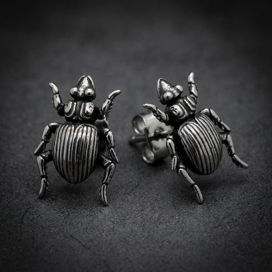 A pair of Scarab Aegis Earrings crafted from shiny 316L stainless steel, featuring detailed scarab beetle designs with a protective, shield-like aesthetic.