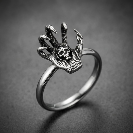 Shadow Hand Ring crafted from dark 316L stainless steel, featuring a skeletal hand with sharp claws gripping a detailed skull, set against a white background.