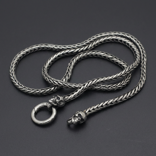 Braided Double Skull Chain Necklace in dark oxidized 316L stainless steel, featuring two skull motifs near the clasp on a rugged braided chain.