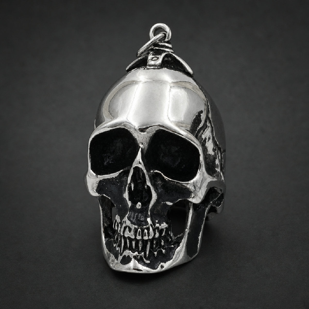 Solid 316L stainless steel skull pendant with blackened eye sockets and mirror polished finish.