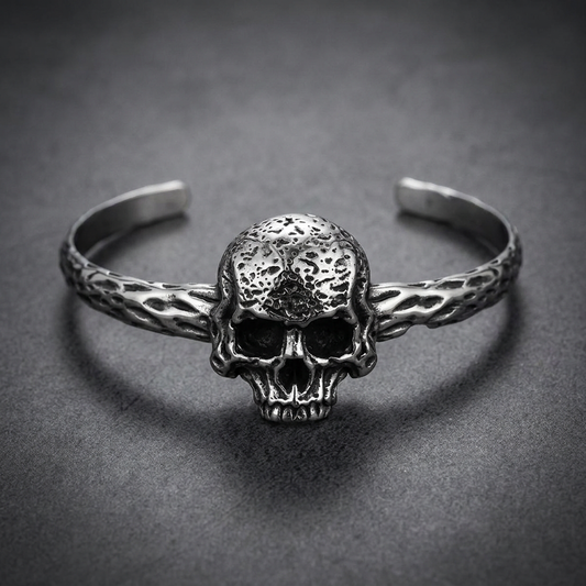 Silver 316L stainless steel skull bracelet with a single, highly textured death's head skull, set on a rugged cuff band with an organic, bark-like texture.