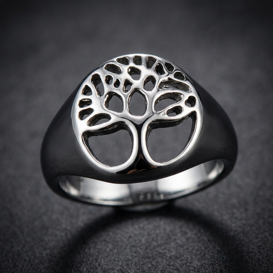 A striking 316L stainless steel Widow Tree Ring, featuring a detailed cut-out of a gnarled, solitary tree silhouette on a robust band, presented against a dimly lit, somber background, highlighting its dark and mysterious aesthetic.