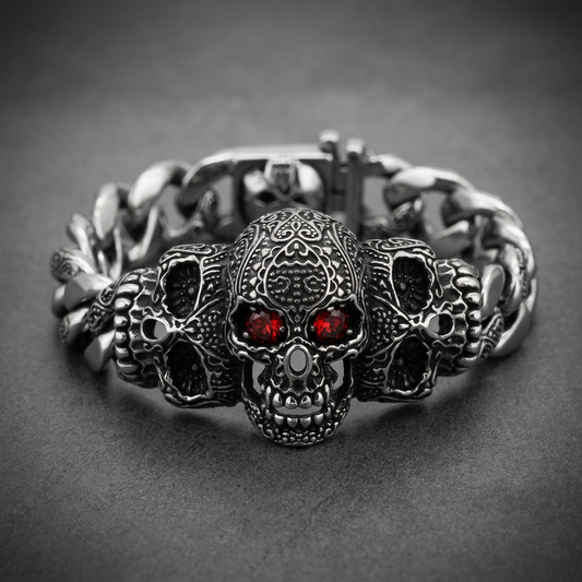 Heavy 316L stainless steel bracelet featuring three detailed skulls with red gemstone eyes on a Cuban link chain.