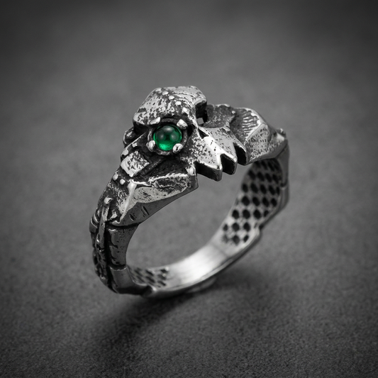 316L stainless steel reptilian ring with jagged teeth and a single green gem eye, worn on a finger